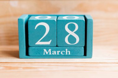 28 Mart. Ahşap zemin üzerinde ay ve tarih olan mavi küp takvimi.