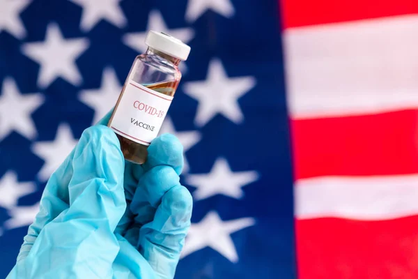Doktorun elleri Amerika Birleşik Devletleri bayraklarında Coronavirus (COVID-19) aşısı tutan eldivenler takıyor, ABD Aşısı