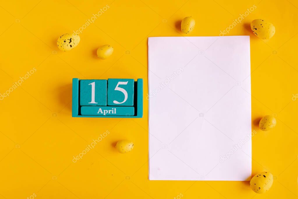 April 15. Blue cube calendar with month date and white mockup blank on yellow background.