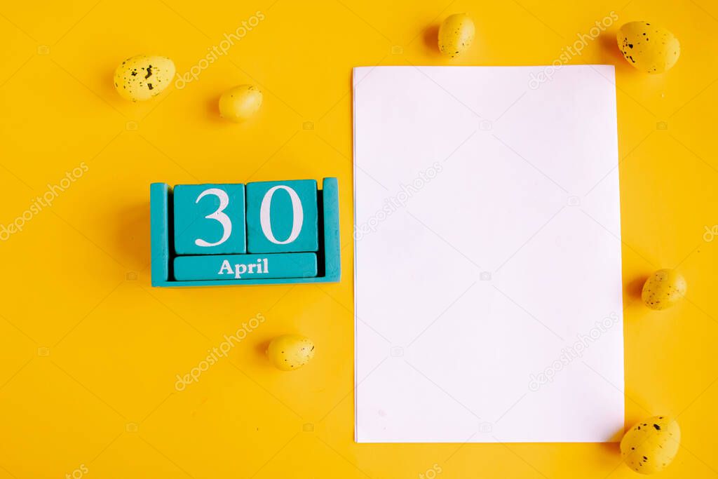 April 30. Blue cube calendar with month date and white mockup blank on yellow background.