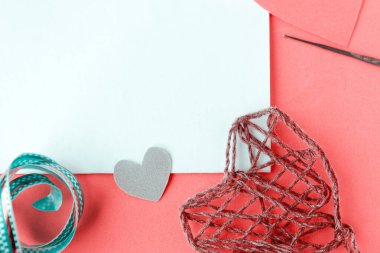 Valentine's Day Handmade Red Thread Hearts, needlework supplies and white mockup blank on pink background. Holiday of Love. Wedding concept. Copy space for the text