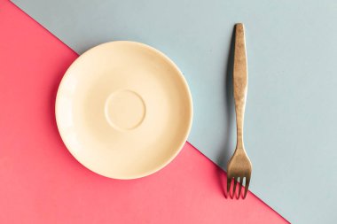 Pembe ve mavi arka planda boş tabak ve çatal. Metin için alanı kopyala. Asgari konsept
