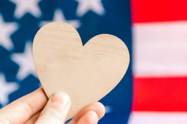 Amerika bayrağının arka planında tahta bir kalp taşıyor. Tasarım için şablon, metin için kopyalama alanı