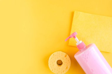 Pembe bulaşık deterjanı ve parlak sarı arka planda süngerler. Minimum konsept. Boşluğu kopyala