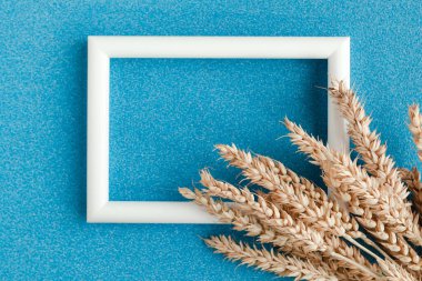 Arka planda buğday kulakları ve fotoğraf çerçevesi var. Minimalizm tarzında tarım kavramı. Metin için alanı kopyala