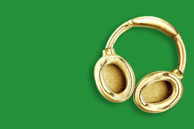 Yeşil arka planda izole edilmiş büyük modern altın kulaklıklar. Minimum konsept. Metin için alanı kopyala