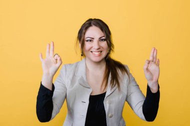 Stüdyodaki sarı izole edilmiş esmer kadının portresi. Kız jest yapıyor.. 