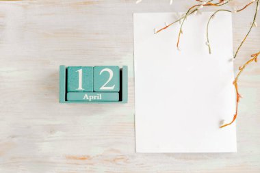 12 Nisan. Ahşap zemin üzerinde ay ve tarih olan mavi küp takvimi.