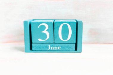 30 Haziran. Ahşap arkaplanda ay tarihi izole edilmiş mavi küp takvimi.