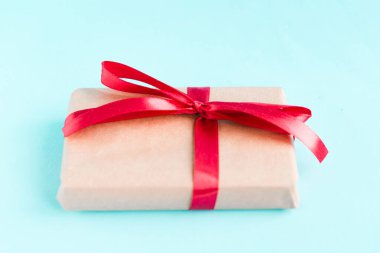 Mavi arka planda parlak kırmızı fiyonklu bir hediye kutusu. Asgari konsept. 