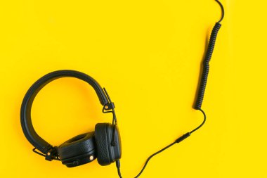 Black big headphones on bright yellow background. 