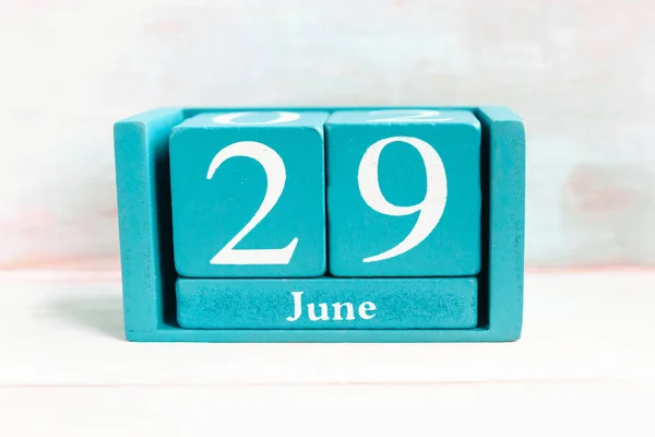 June 29. Blue cube calendar with month date isolated on wooden background.