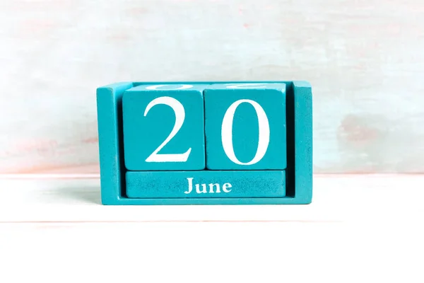 June 20. Blue cube calendar with month date isolated on wooden background.