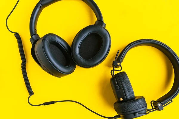 Big black headphones on bright yellow background.