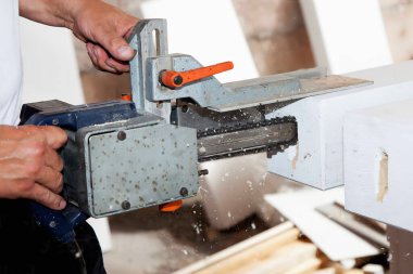 Marangoz testere ve tahtayla çalışıyor.