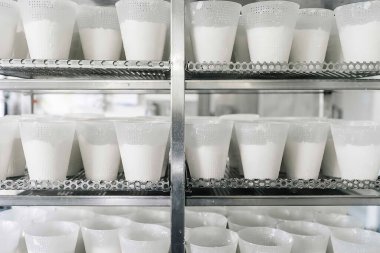 Fabrikanın rafında macunlu konteynırlar var.