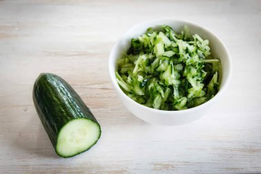 Masadaki kasede taze salatalık ve salata var.