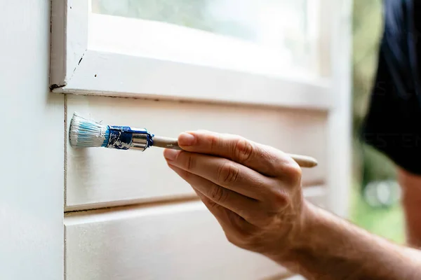 Adam kapıyı beyaz renge boyuyor fırçayla