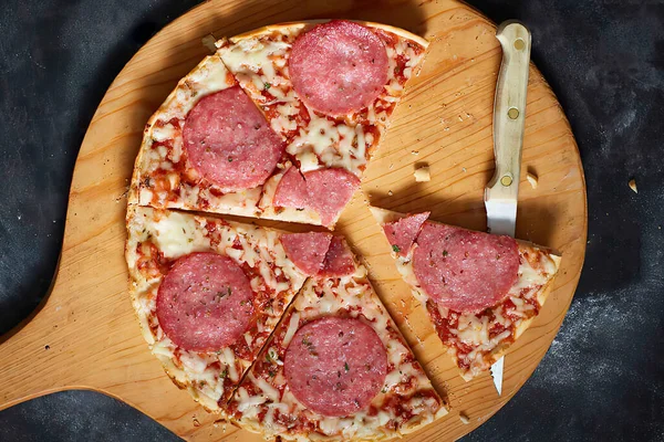 Kesme tahtasında dilimlenmiş lezzetli pizza, üst manzara.