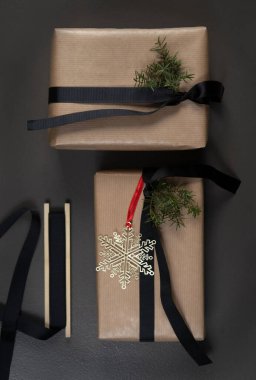 İçinde el işi kağıt ve siyah kurdele olan Noel hediyesi kutuları. Altın kar tanesi dekorasyonu. Siyah arka plan dikey fotoğraf.