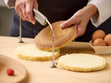 Ev yapımı pasta için pasta katmanları oluşturan kadın, tatlı montajı için sünger bazlı hazırlama ile mutfakta pişirme işlemi.