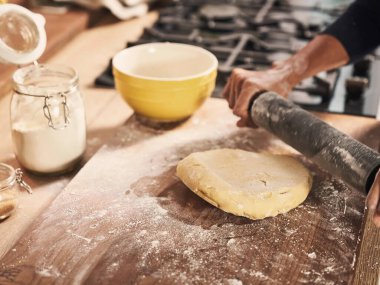 Mutfak masasında merdaneyle hamuru yuvarlayan kadınların ellerini kapatın, ev yapımı hamur işleri için pişirme işlemi.