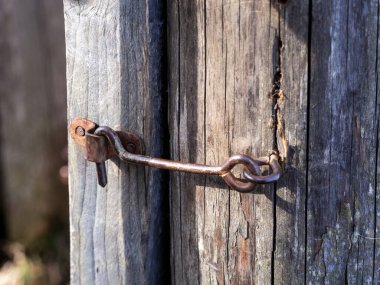 Eski günlerde güvendeydik. Eski gri kapı metal bir kancaya kilitlendi. Yakın plan fotoğraf.