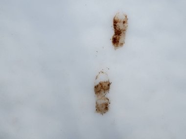 Bakir beyaz kar yüzeyinde kirli çamur ayak izleri.