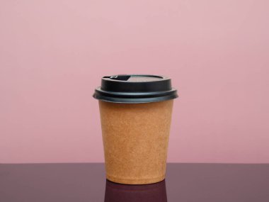 Masadaki tek kullanımlık fincanda kahve ve pembe arka plan. Metin için boşluk