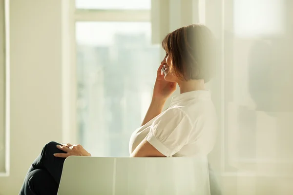 Вид сбоку улыбающейся деловой женщины, разговаривающей по телефону — стоковое фото