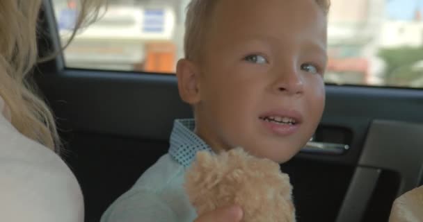 Garçon avec peluche jouet sur le siège arrière de voiture — Video