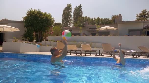 Hombre y mujer jugando con la pelota en la piscina — Vídeo de stock