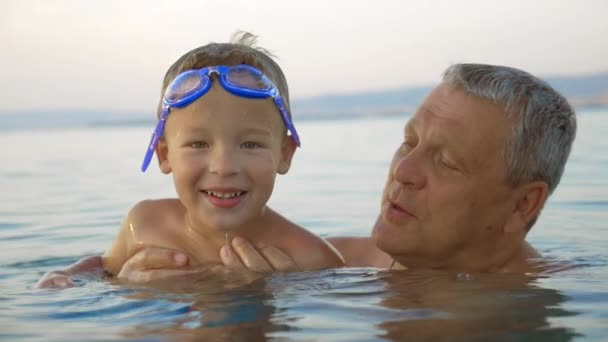 Kind und Großvater baden im Meer — Stockvideo