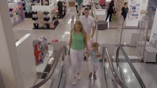 Young family with child riding escalator in shopping center — Stock Video