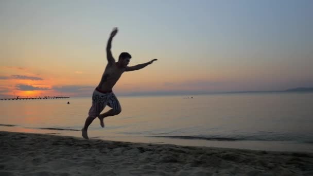 Akrobasi deniz kenarında günbatımı sırasında gösterilen adam — Stok video