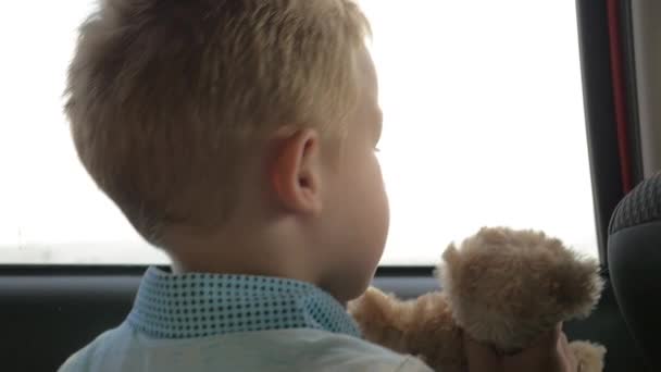 Ребенок путешествует в машине с любимым плюшевым мишкой — стоковое видео