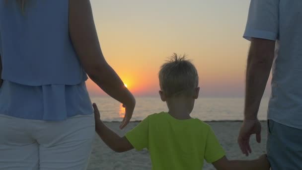 Rodina s dítětem při pohledu na západ slunce nad mořem — Stock video
