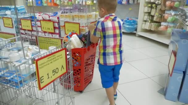 Pequeno menino rolando carrinho de compras no supermercado — Vídeo de Stock