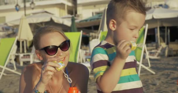 Mor och barn blåsa bubblor på stranden — Stockvideo