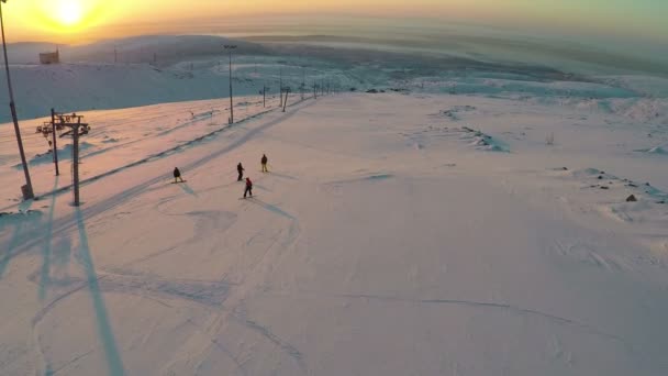 Vista aérea de esquiadores y snowboarders al atardecer — Vídeos de Stock