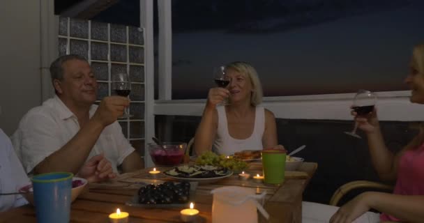 Люди наслаждаются едой и вином во время домашнего ужина — стоковое видео