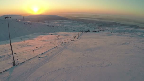 Skidbacke och snöiga kullar på solnedgången, aerial view — Stockvideo