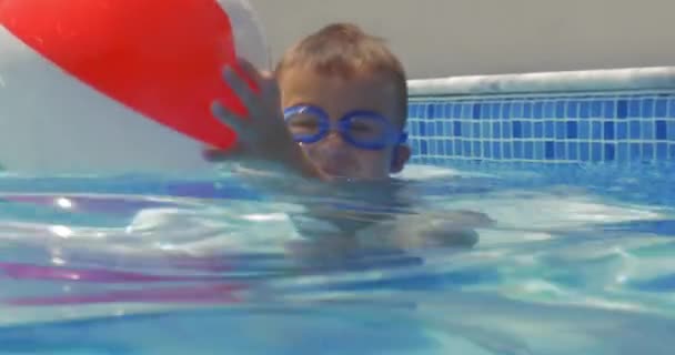 Pequeño niño juguetón con pelota en la piscina — Vídeos de Stock
