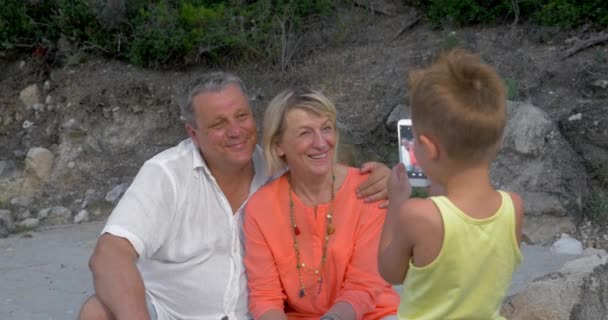 Ребенок фотографирует бабушку и дедушку с помощью мобильного телефона — стоковое видео