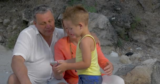 Chłopiec i dziadków patrząc na zdjęcia na smartphone — Wideo stockowe