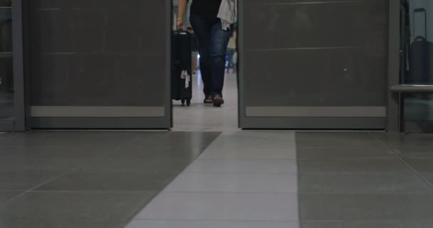 Люди с сумками, проходящими через автоматические двери — стоковое видео