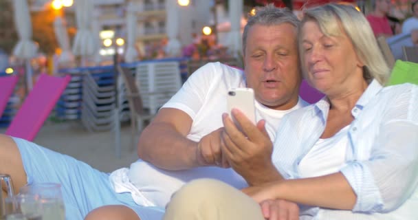 Pareja madura usando teléfono inteligente en la playa — Vídeos de Stock