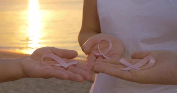 Mulheres com fitas de consciência rosa ao ar livre ao pôr do sol — Vídeo de Stock