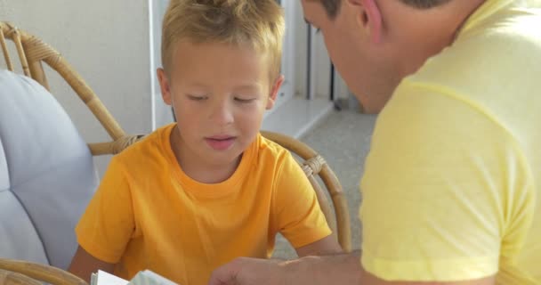 Çocuk ve babası balkonda kitap okuma — Stok video
