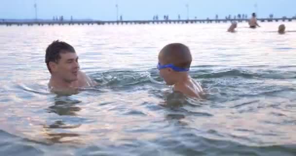 Junge schwimmt mit Eltern im Meer — Stockvideo